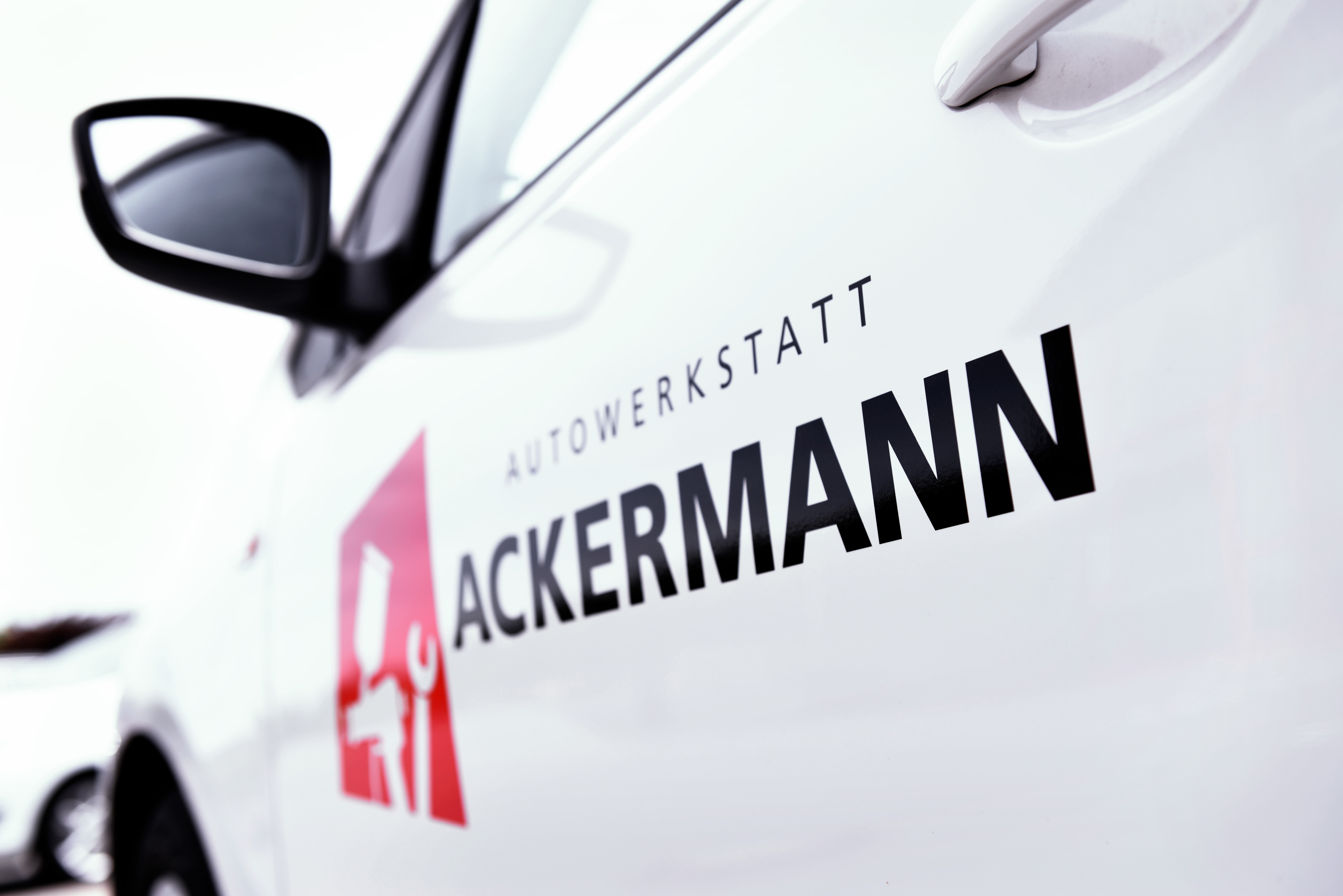Weißes Servicefahrzeug mit dem Logo und Namen von Autowerkstatt Ackermann, einem breit aufgestellten KFZ-Fachbetrieb.