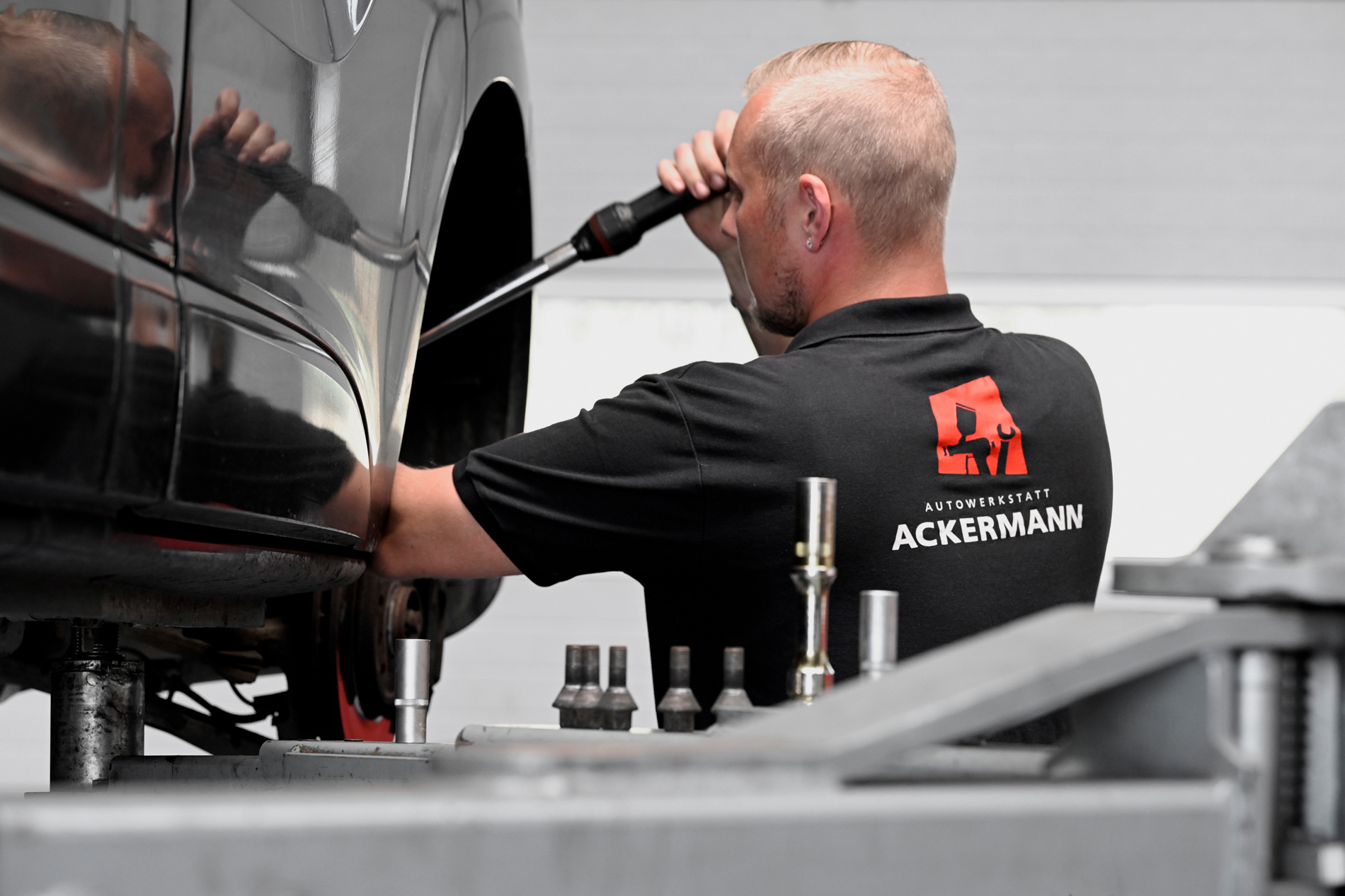 Ein Mechaniker von Autowerkstatt Ackermann, einem KFZ-Fachbetrieb für Werkstattservice, Lackiererei und weitere Dienstleistungen, arbeitet an einem Fahrzeug in der Werkstatt.